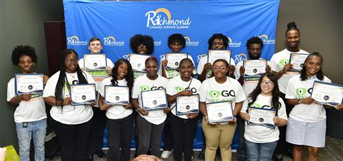 Group of people smiling and holding certificates inside. 